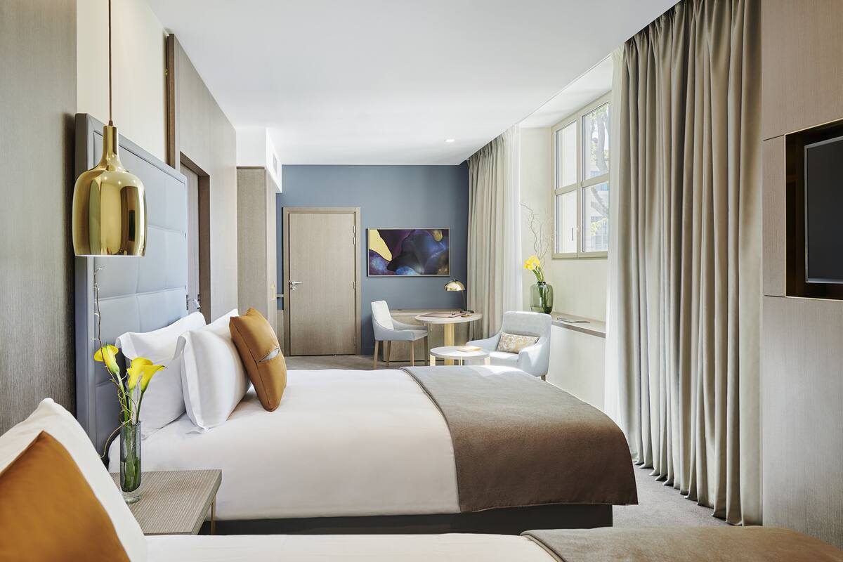 A modern hotel room with a large bed, a desk, and a TV.