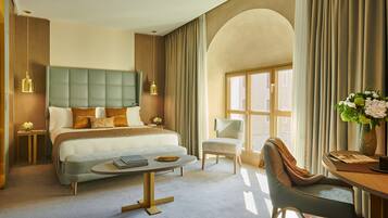 A modern hotel room with a large bed, a sitting area, and a desk.