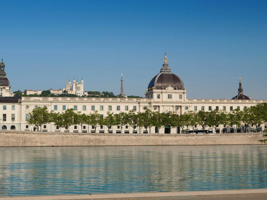 A large building with a prominent dome and a river in the foreground.