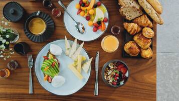 Café da manhã com diversas comidas e bebidas sobre uma mesa de madeira.