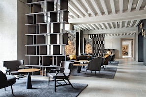Un interior moderno con una estantería central, zona de estar y vista hacia un comedor.