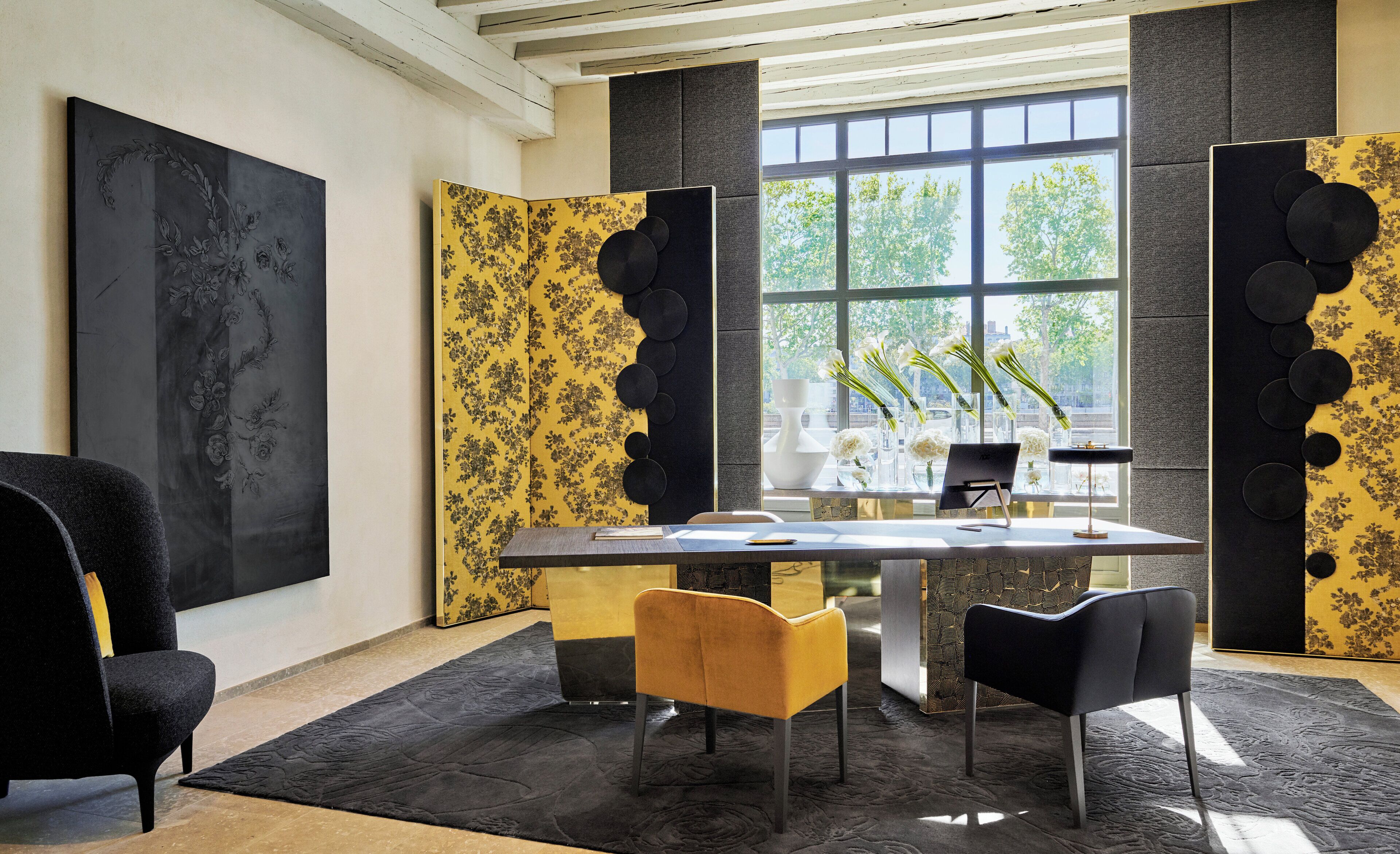 A modern office space with a large desk, two chairs, a large window, and decorative wall panels.