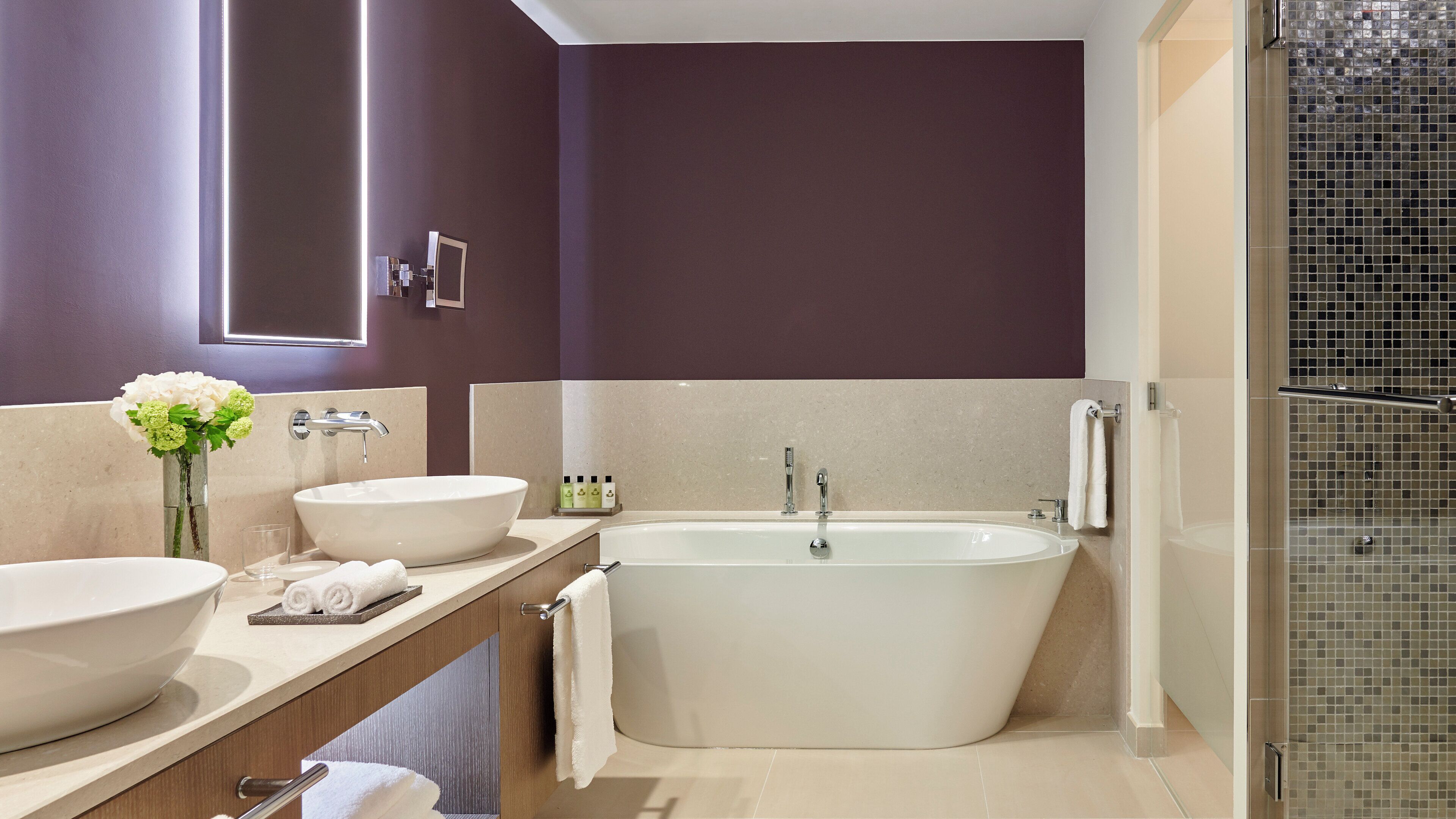 Une salle de bain moderne avec deux vasques, une baignoire sur pieds et une douche à parois de verre.