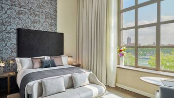 Una habitación de hotel moderna con una cama grande, vistas a la ciudad, una ventana con cortinas y una pequeña mesa junto a la ventana.