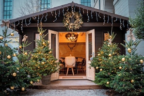 A cozy cabin with a wooden exterior, a welcoming entrance, and two Christmas trees adorned with golden ornaments. - Intercontinental Lyon Hotel Dieu by IHG (Lyon)