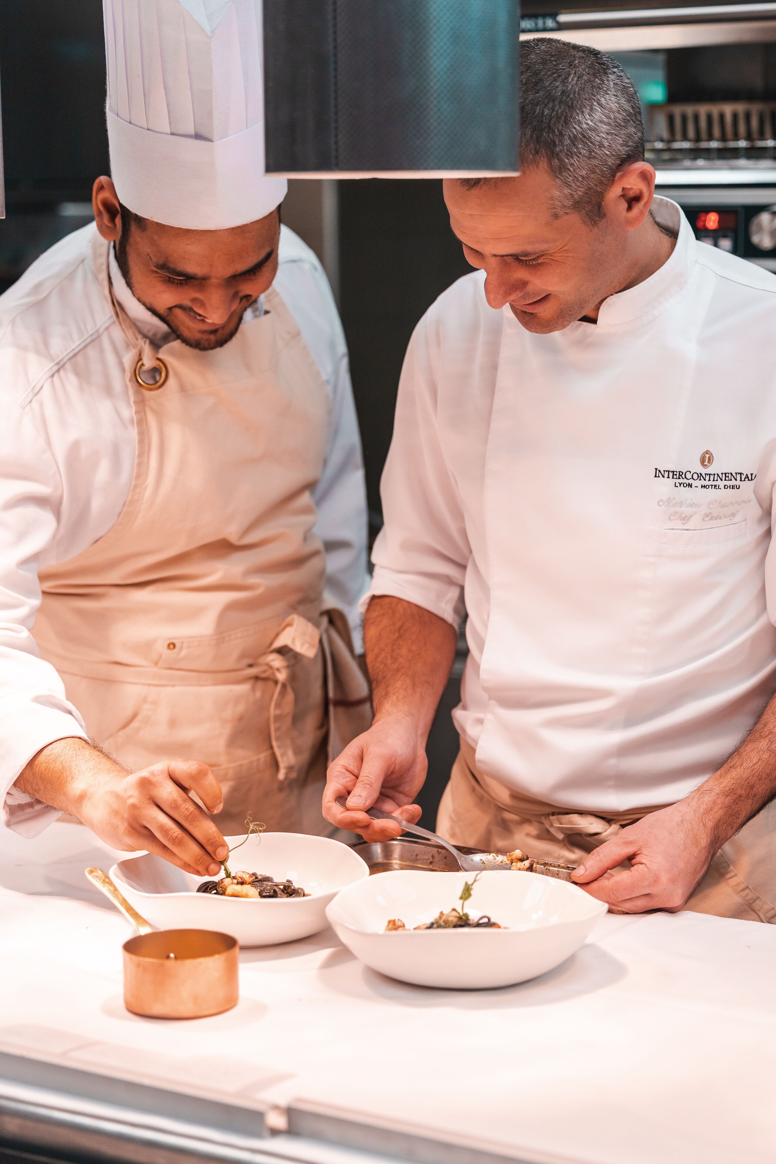 Dois chefs a preparar comida numa cozinha profissional.