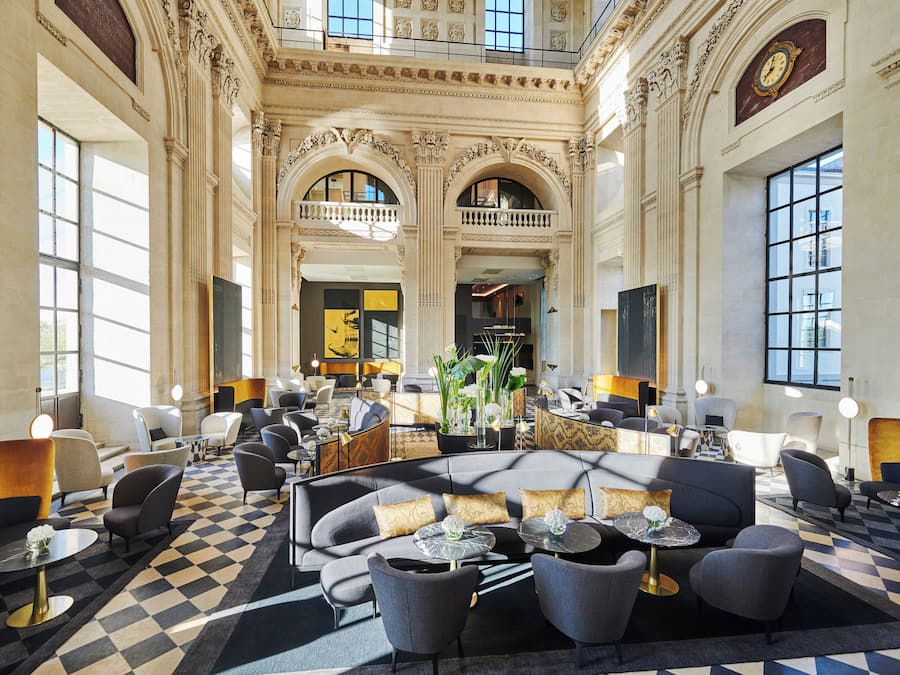 A spacious lobby with high ceilings, ornate columns, and a checkered floor.