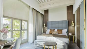 A modern bedroom with a large bed, bedside tables, a desk, and a chair.