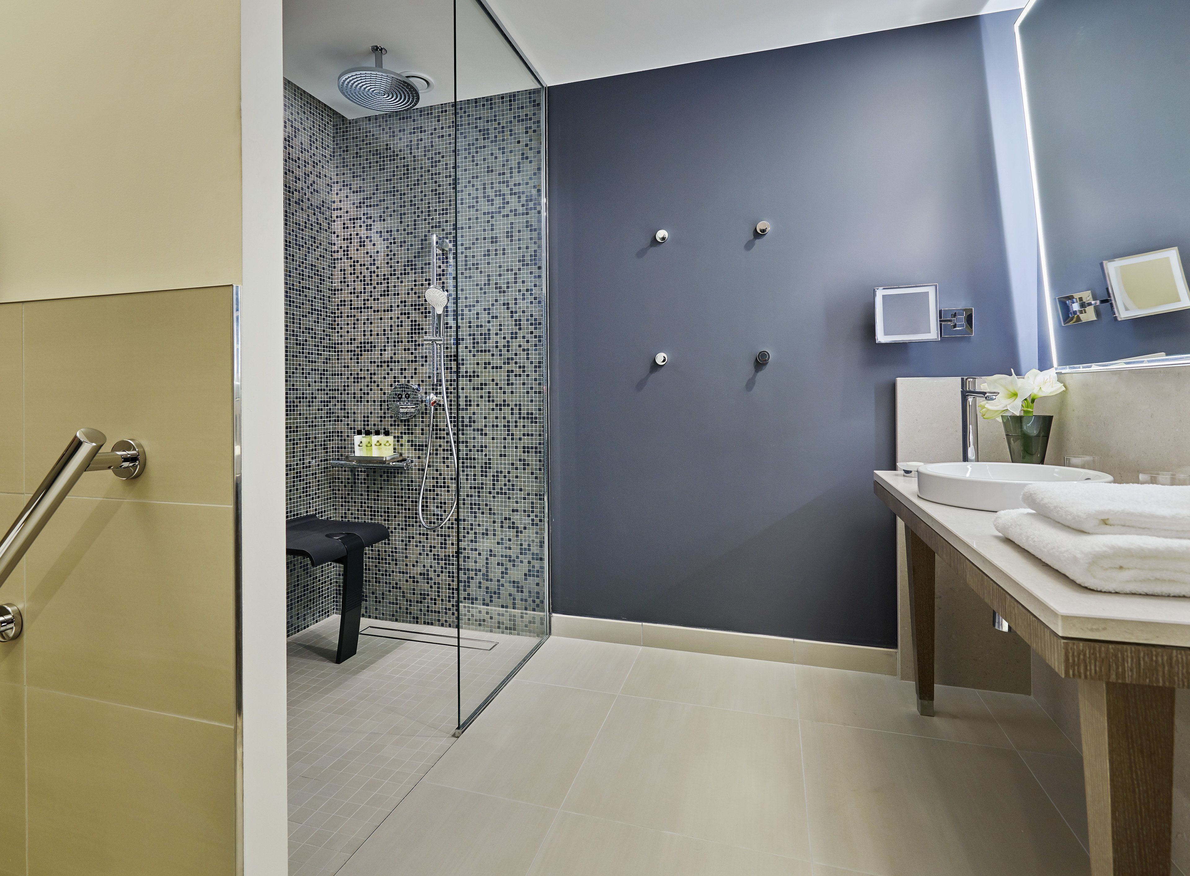 Un baño moderno con ducha, lavamanos con espejo e inodoro.
