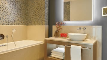 A modern bathroom with a bathtub, a vanity with a large sink, and a mirror.