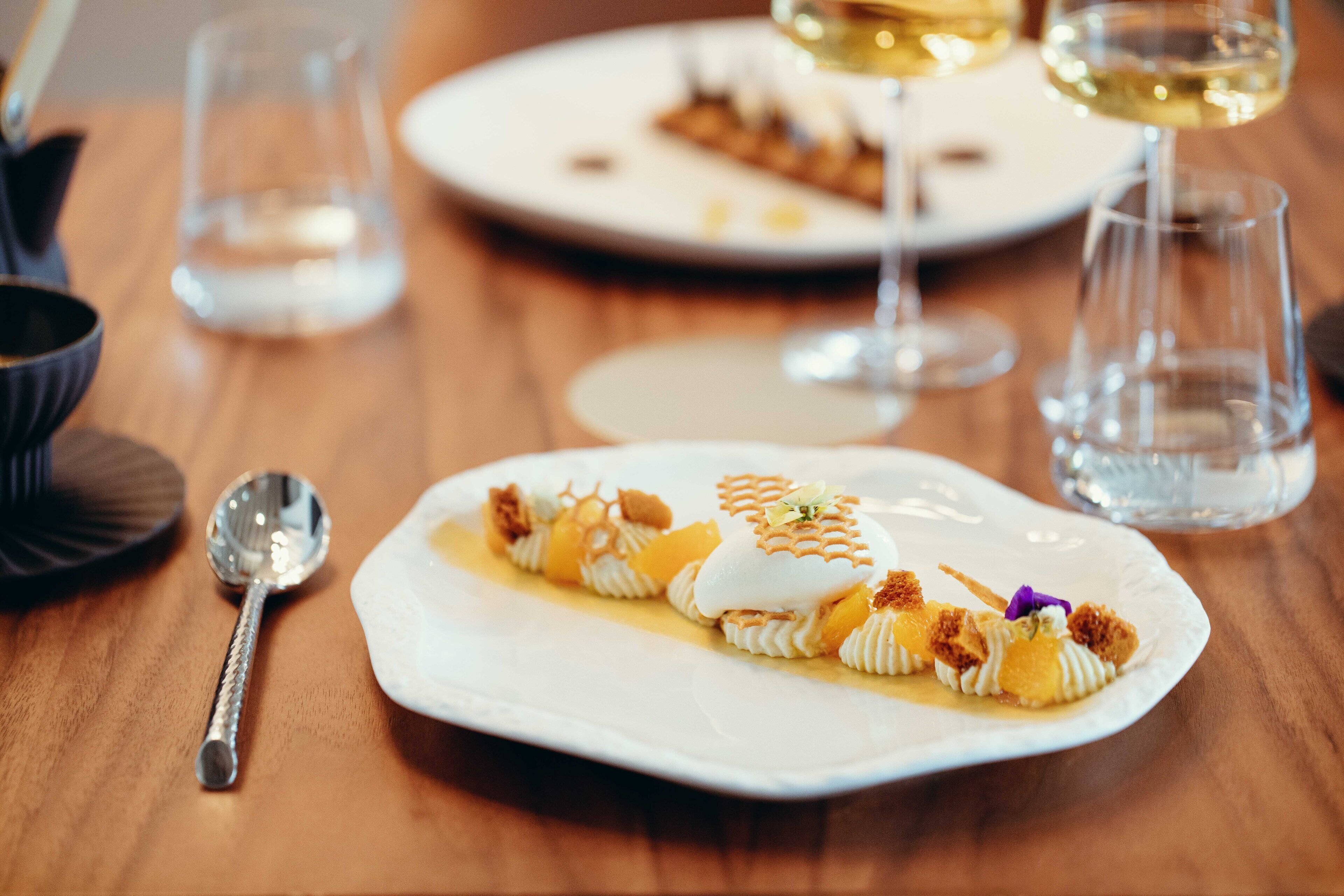 A dessert plate with a spoon and glasses on a wooden table.