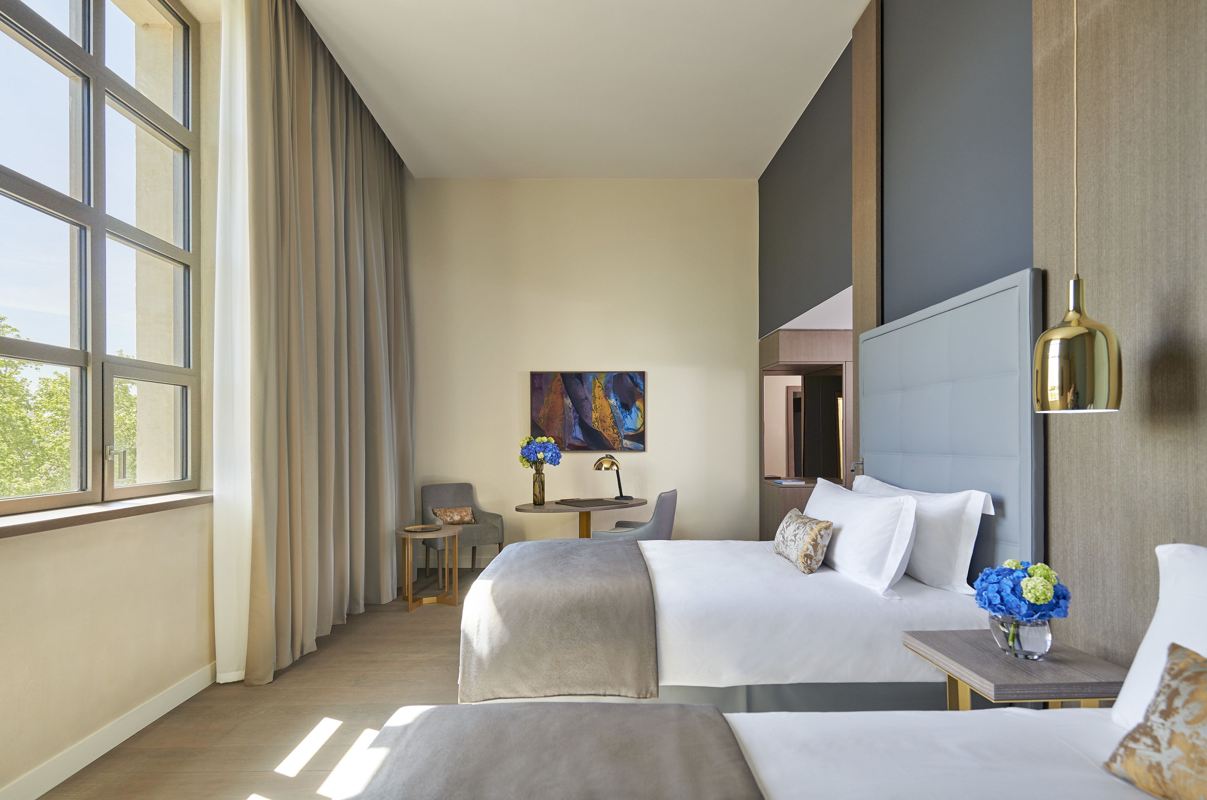 A hotel room with two beds, a desk, and a chair.