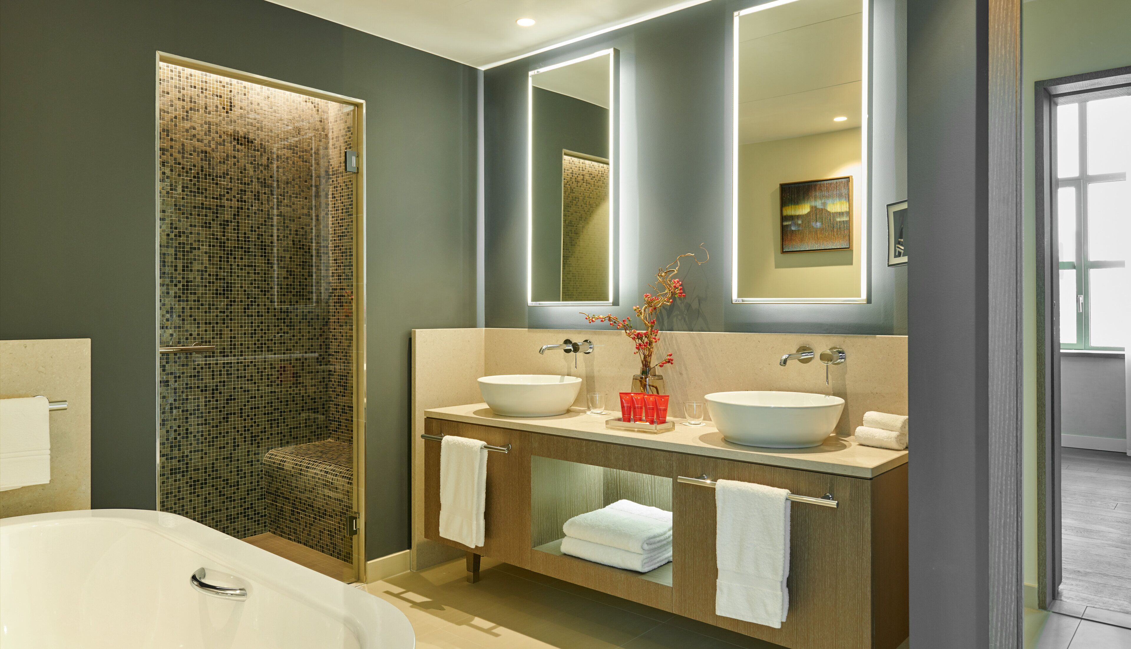 A modern bathroom with a glass-enclosed shower, two sinks, and a large mirror.
