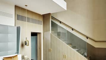 Une chambre d’hôtel moderne avec un grand lit, un escalier en verre et une vue sur le ciel.