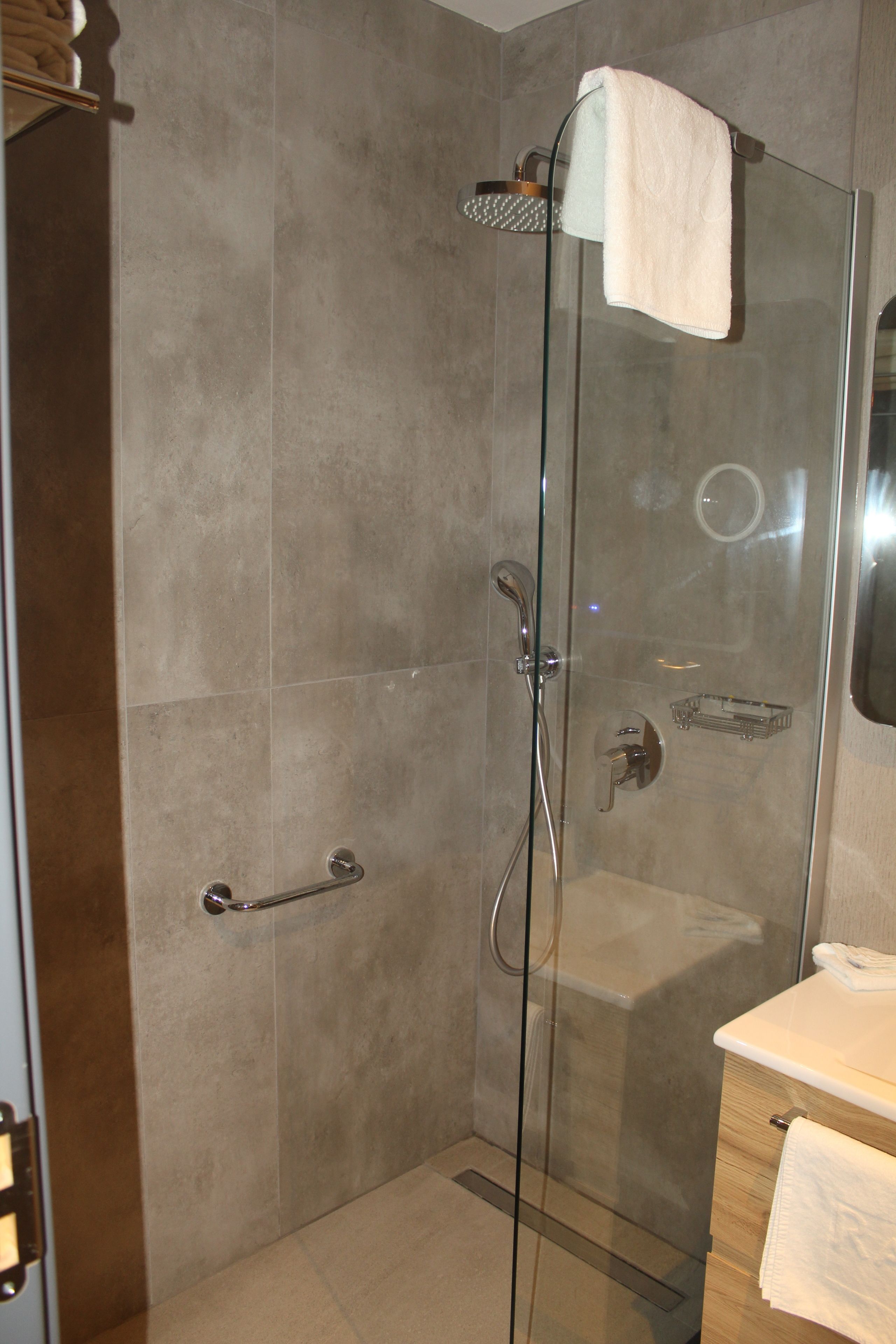 Un baño moderno con ducha acristalada, toallero y lavabo con espejo.