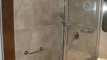 Un baño moderno con ducha acristalada, toallero y lavabo con espejo.