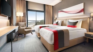 A modern hotel room with a large bed, a desk, a chair, and a TV. - Ramada by Wyndham Tire (Tire)