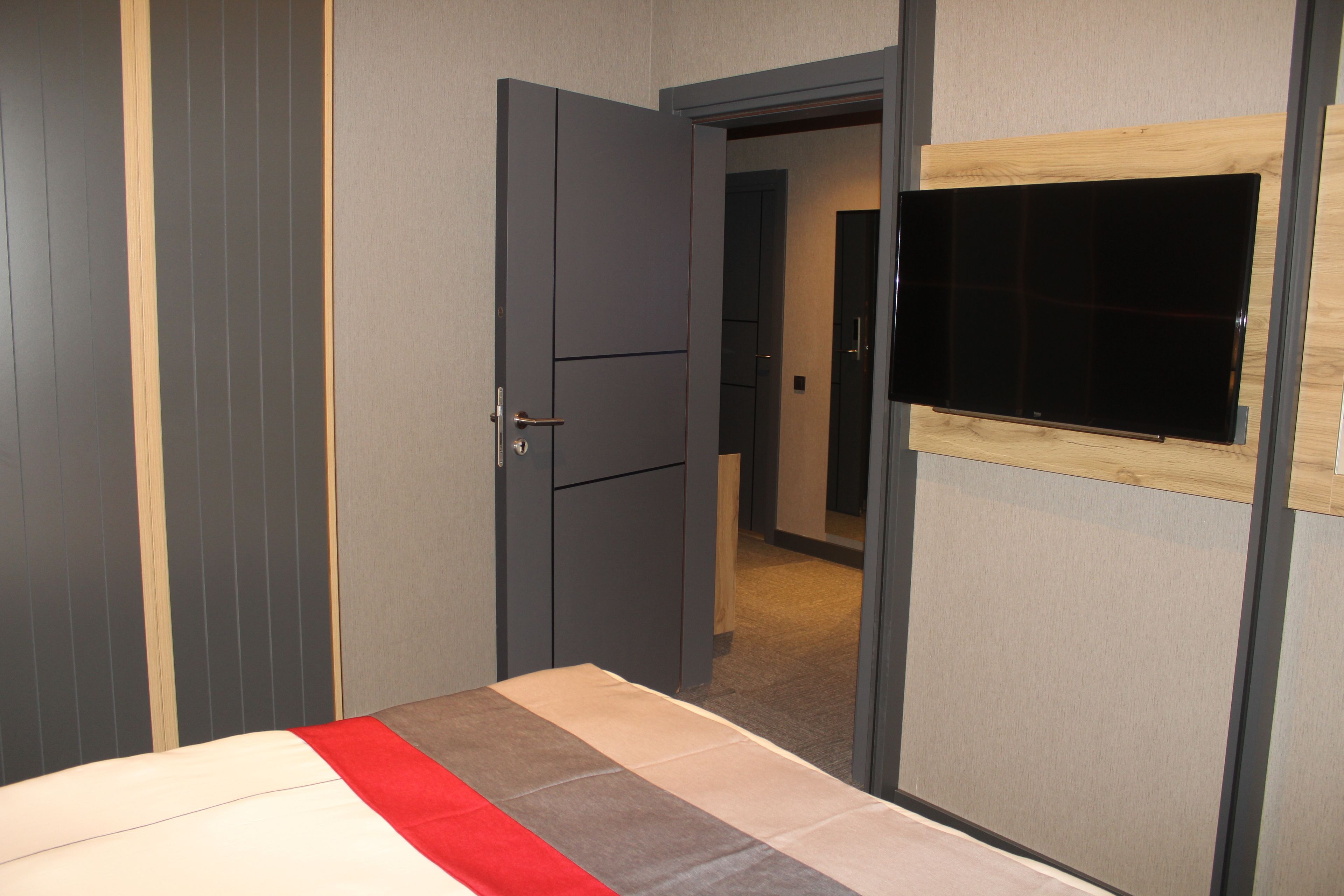 Un dormitorio con una cama, un armario y un televisor fijado a la pared.