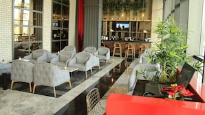 A modern lobby with a bar area, seating with sofas and chairs, and a large plant. - Ramada by Wyndham Tire (Tire)