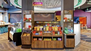 A snack kiosk with a variety of snacks and drinks, a 24/7 market sign, and a 'check out our local items' sign. - TRU BY Hilton Edmonton Windermere (Edmonton)