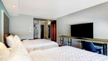 Habitación de hotel con dos camas, un escritorio con una silla, televisión y una cinta de correr al fondo.