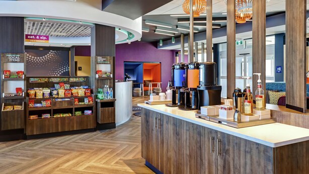 A modern hotel lobby with a coffee station, snack bar, and a 24/7 market sign. - TRU BY Hilton Edmonton Windermere (Edmonton)