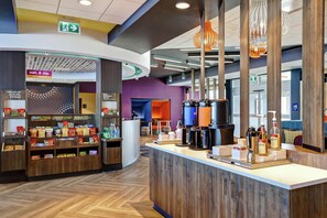 A modern hotel lobby with a coffee station, snack bar, and a 24/7 market sign. - TRU BY Hilton Edmonton Windermere (Edmonton)