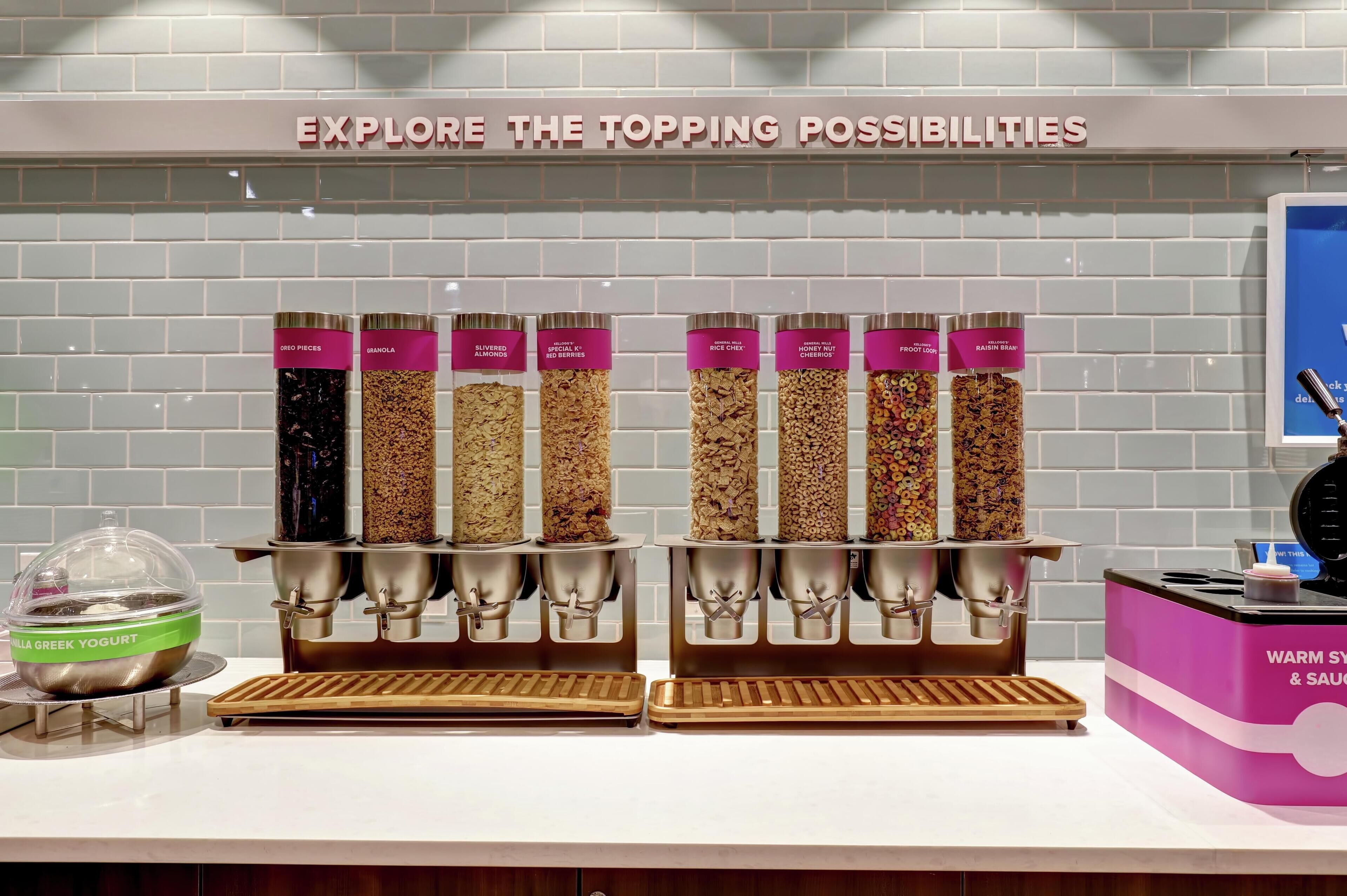Una estación de comida con diferentes opciones de cobertura como yogur griego, granola y frutos rojos.