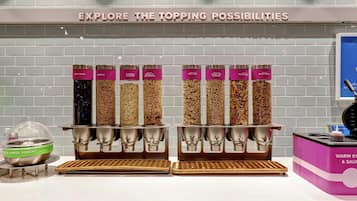 Una estación de comida con diferentes opciones de cobertura como yogur griego, granola y frutos rojos.