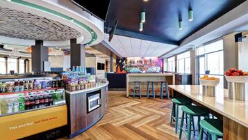 A modern food court with a variety of food options, seating areas, and a large window providing natural light.