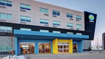 A modern hotel with a flat roof, large windows, and a prominent 'tru by Hilton' sign.