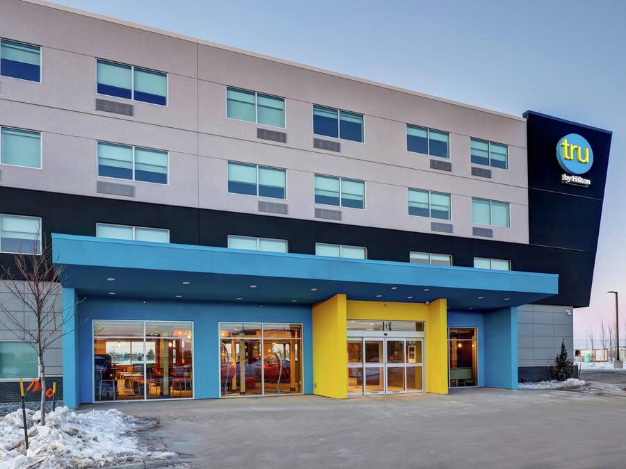 A modern hotel with a flat roof, large windows, and a prominent 'tru by Hilton' sign.