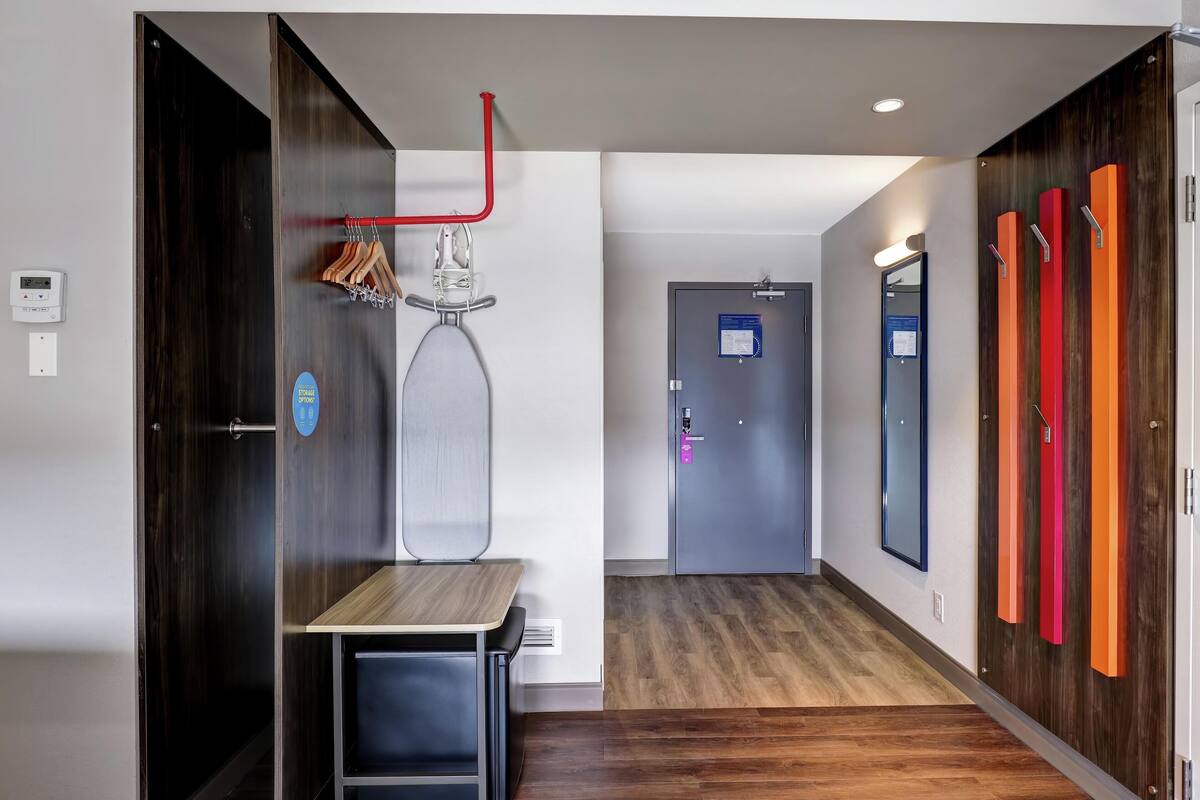 A hotel hallway with a coat rack, a table, and a door with a sign.