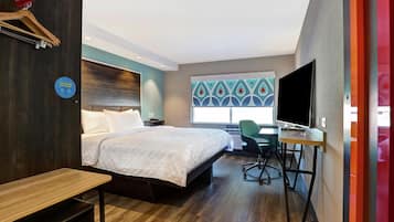 Habitación de hotel con cama, escritorio, silla, televisión y ventana con vistas.