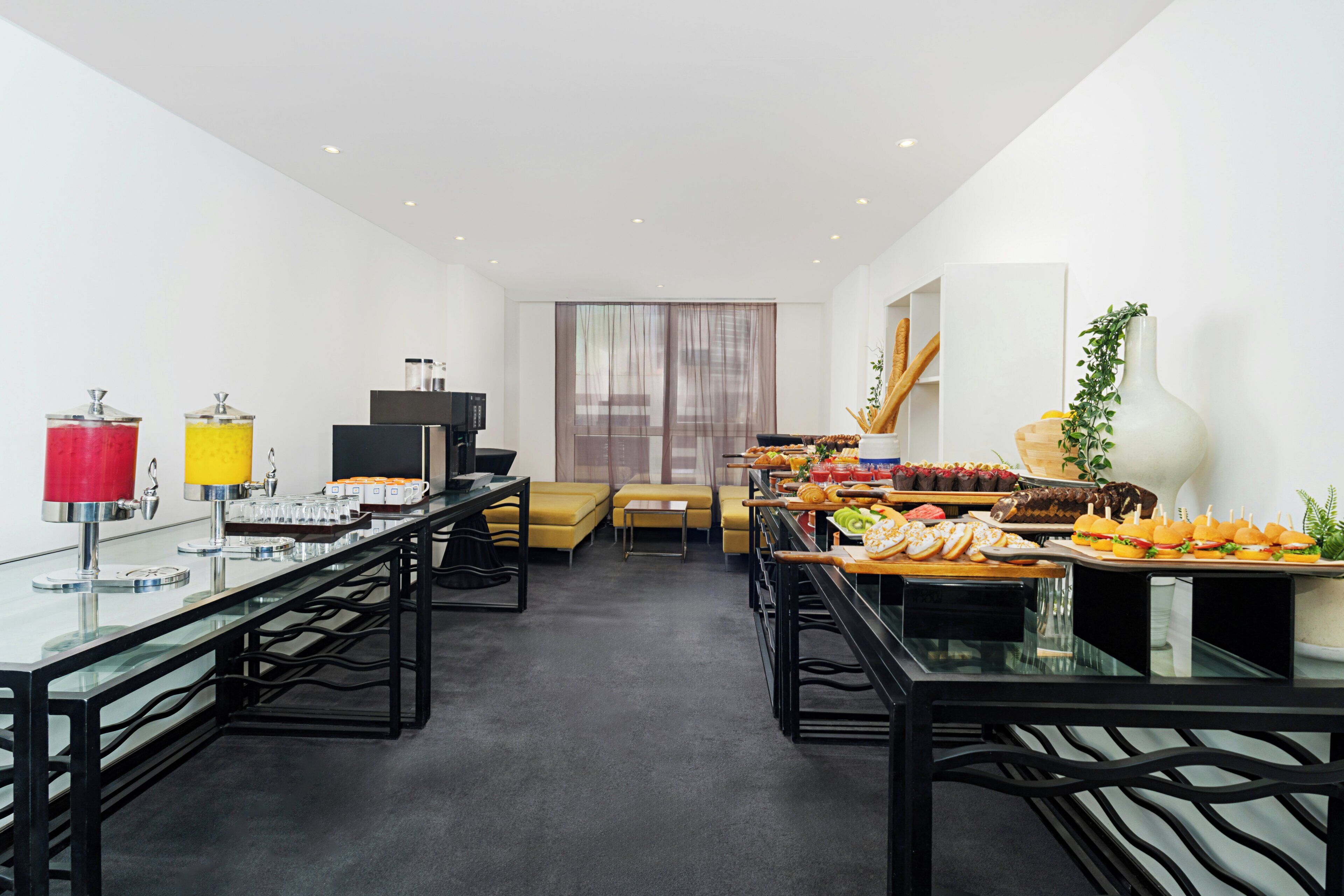 Une chambre d’hôtel moderne dotée d’un coin repas avec un buffet proposant divers plats, d’un canapé et d’une télévision.