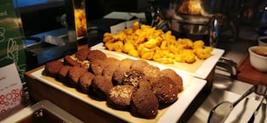 Un bufé con bandejas de galletas y alimentos fritos.