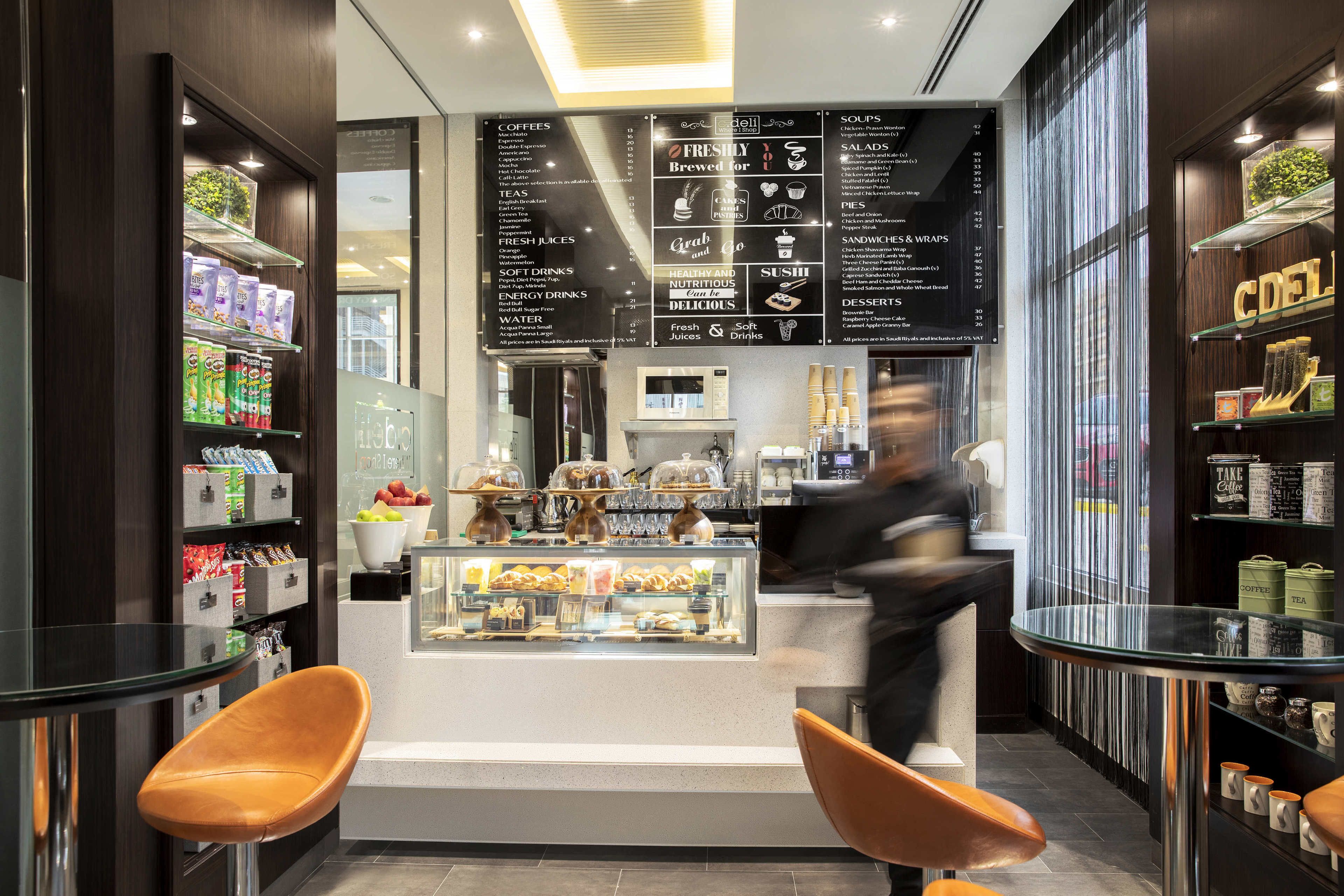 A modern café with a menu board, seating area, and various food and drink displays.