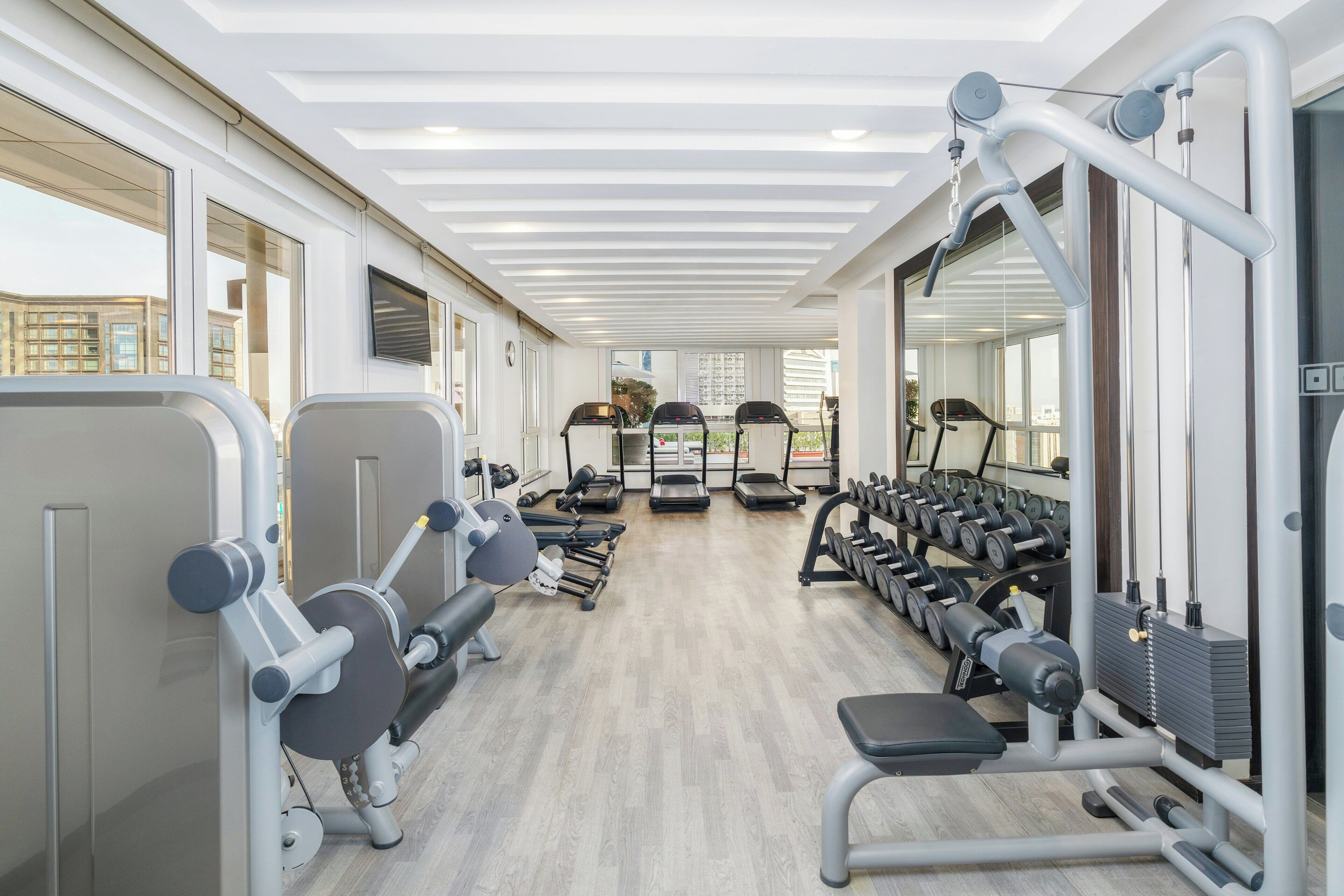 A gym with exercise equipment, treadmills, and dumbbells.