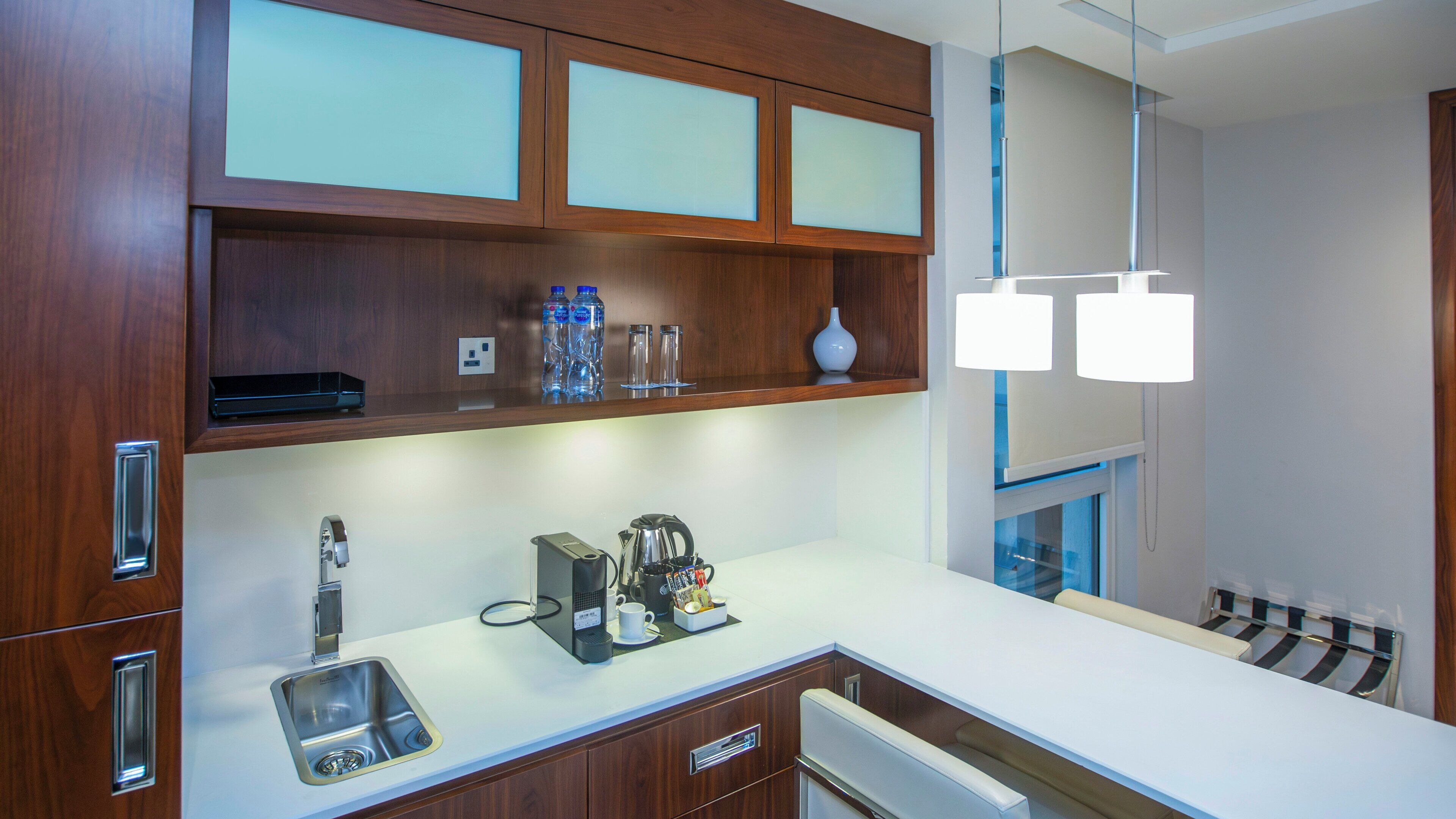 A modern kitchen with wooden cabinets, a stainless steel sink, and a white countertop.