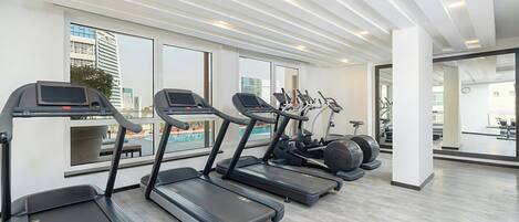 Un gimnasio con cintas de correr, elípticas y equipo de pesas.