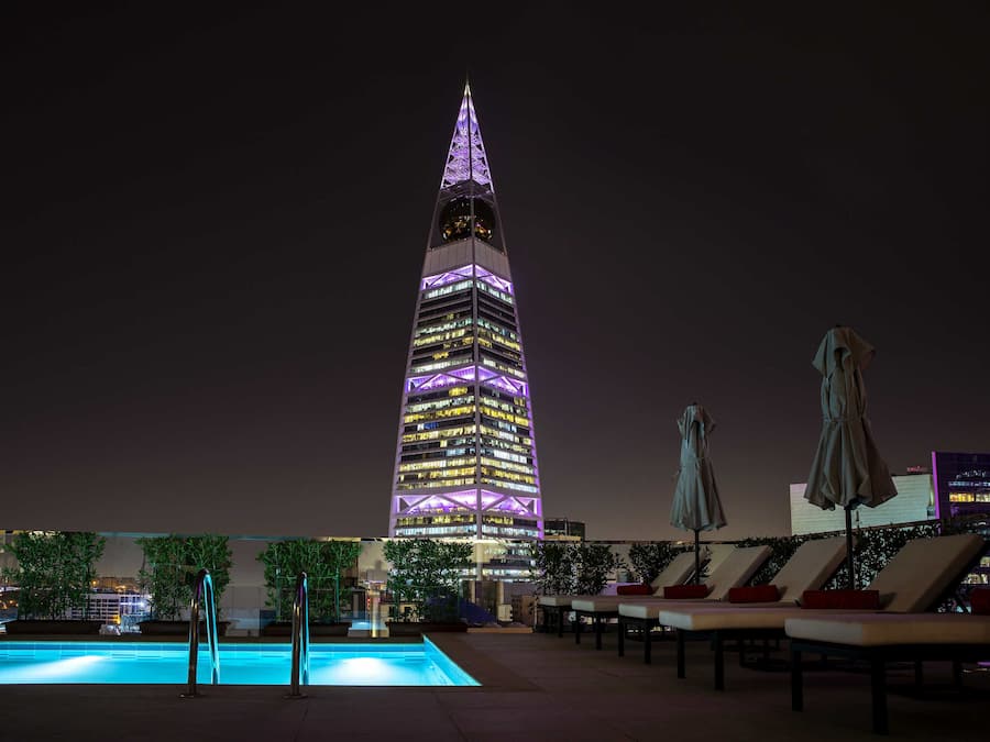 Una piscina al aire libre, sombrillas, sillones reclinables de piscina