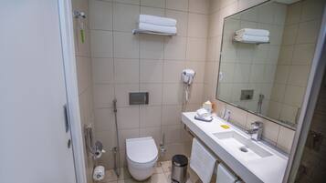 A modern bathroom with a toilet, bidet, towel rack, and a hairdryer.