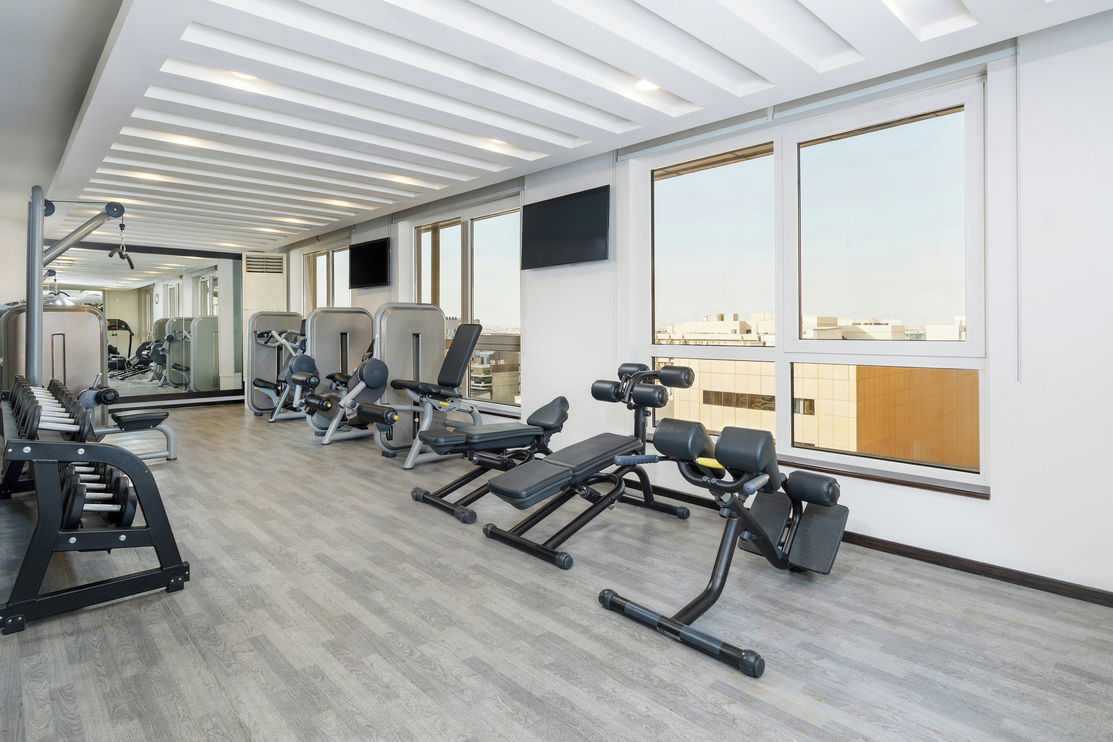 A gym with exercise equipment, large windows, and a modern ceiling design.