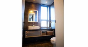 A bathroom with a large mirror, a sink, and a toilet.