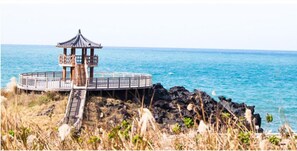 A gazebo-style structure with a circular railing, situated on a rocky outcrop by the sea.