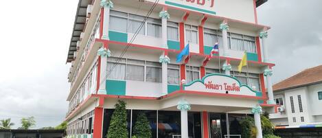 A multi-story building with a red and white facade, a sign reading "Hotel", and multiple flags.