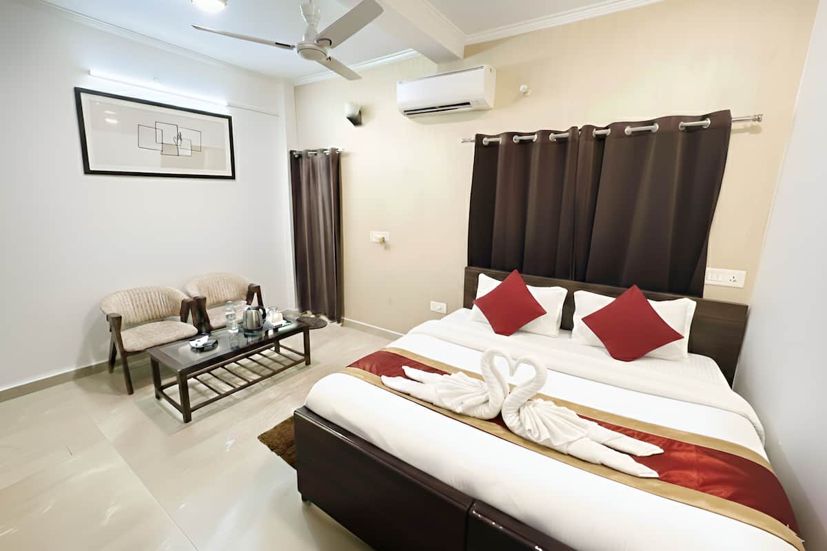 A hotel room with a bed, a desk, a chair, a ceiling fan, and an air conditioning unit.