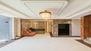A spacious lobby with a modern chandelier, a reception desk, and a seating area. - Krishna Residency - A Boutique Hotel (Bareilly)