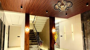 A modern interior with a staircase, wooden panel ceiling, and a chandelier. - Krishna Residency - A Boutique Hotel (Bareilly)
