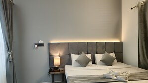 A modern hotel room with a large bed, a bedside table with a lamp, and a wall-mounted light above the bed. - Krishna Residency - A Boutique Hotel (Bareilly)